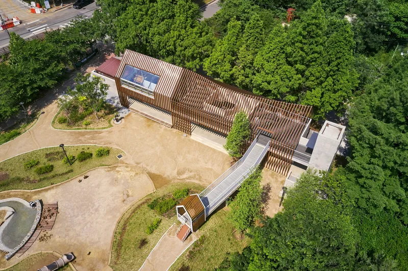 Aerial view of the timber-slatted roofscape with gabled volumes connected by an elevated walkway