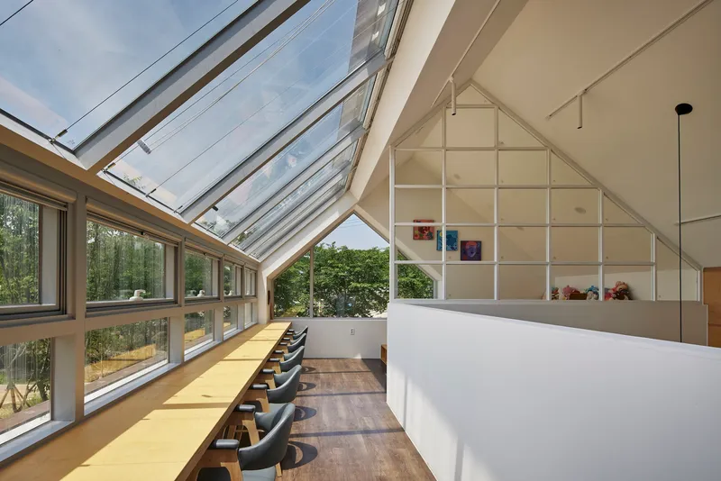 Interior space beneath a glazed pitched roof with yellow counter and built-in shelving