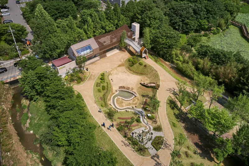 Aerial view of the serpentine water feature and planted mounds surrounded by forest canopy