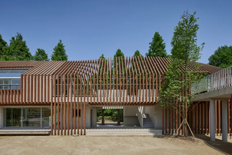 Central courtyard with densely spaced vertical timber columns framing a passage between planted areas