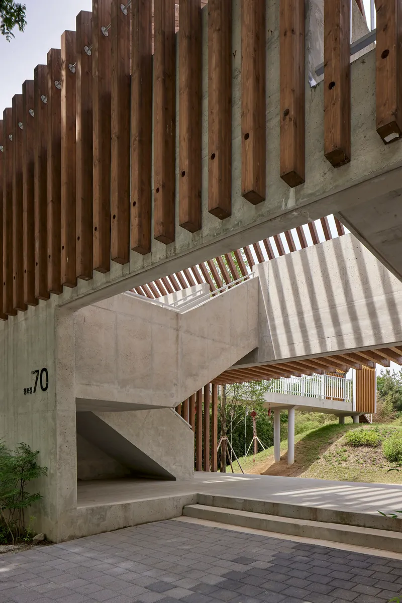 Vertical timber louvers casting stripes of shadow on concrete walls and steps below
