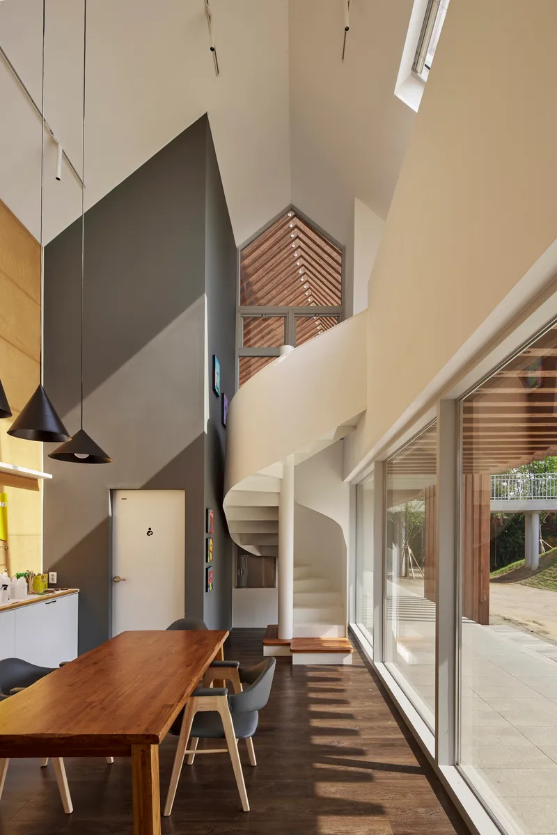 Interior dining space with black stovepipe, spiral stair, and sunlight striping the floor