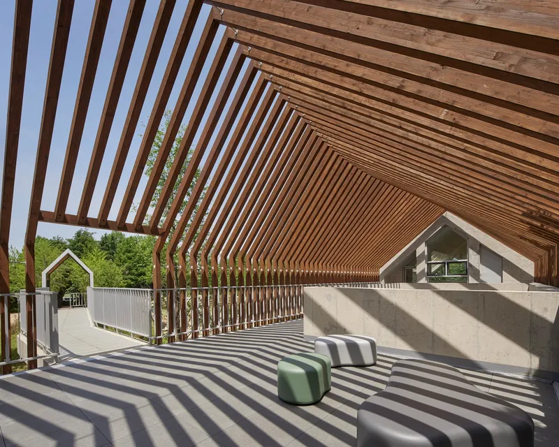 Timber-slatted roof canopy creating shadow patterns on a terrace seating area