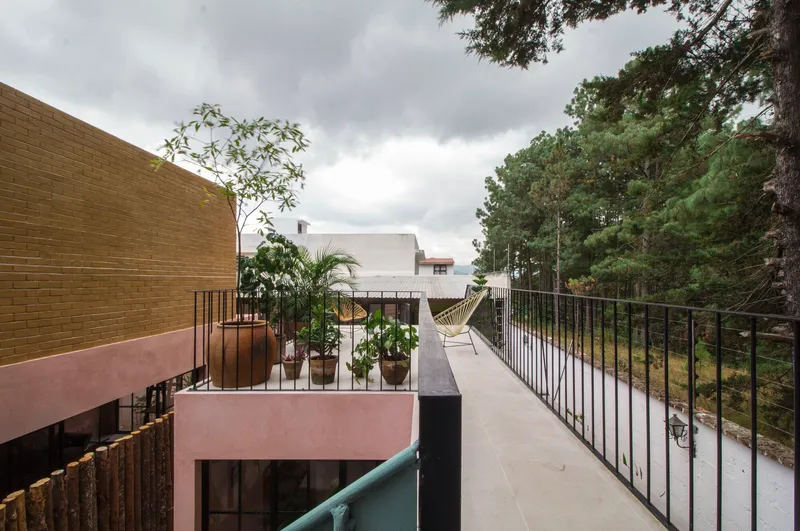 Upper terrace with metal railings, potted plants, and hammock under overcast sky