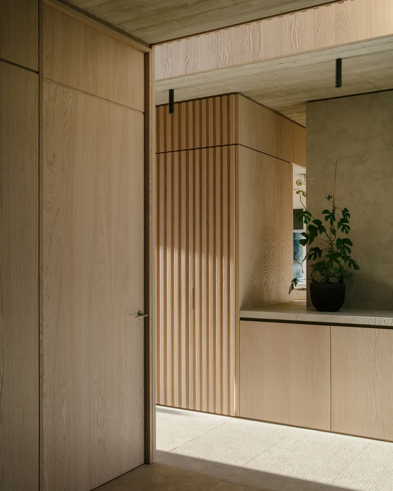 Flush timber door and slatted wall detail beside a low bench with potted plants