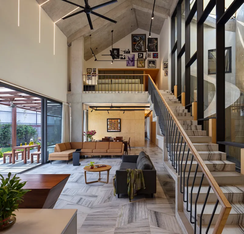 Double-height living room with cantilevered concrete staircase and skylights in the gabled ceiling