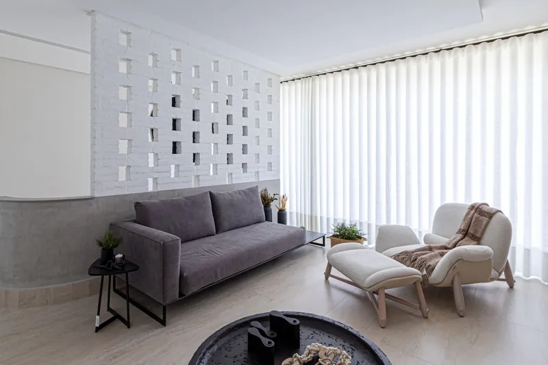 Living room with perforated white brick screen wall and full-height curtains filtering natural light