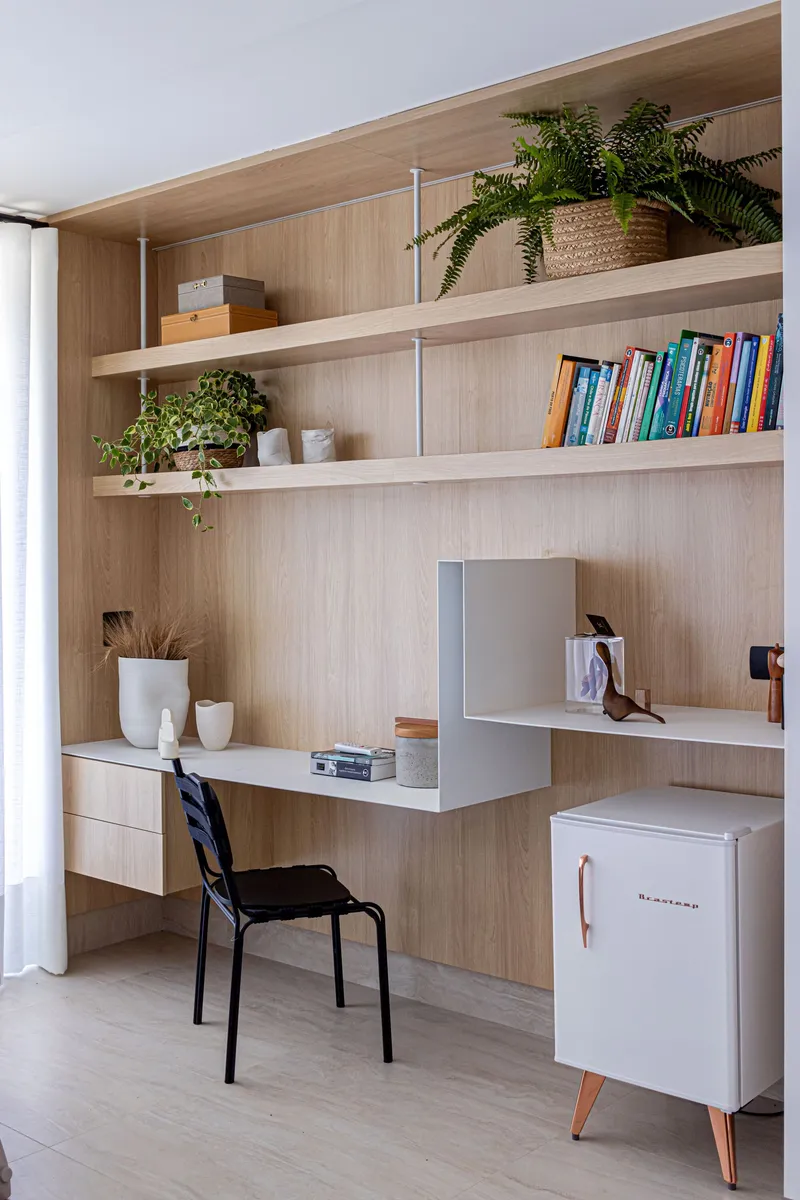 Built-in timber desk with integrated shelving and potted plants beside a white curtain