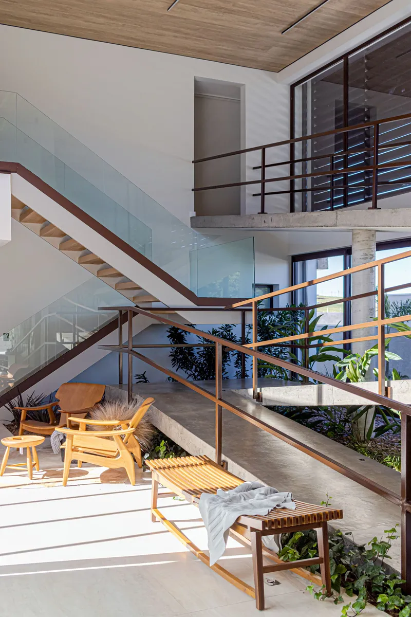 Interior courtyard with timber stair and steel railings beneath a double-height void in daylight