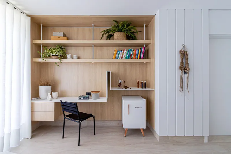Recessed workspace niche with timber shelving and white cabinetry beside a vertical slat partition