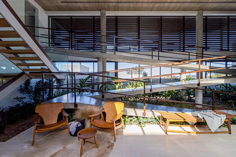 Seating area beneath concrete footbridge with planted bed and dappled sunlight filtering through