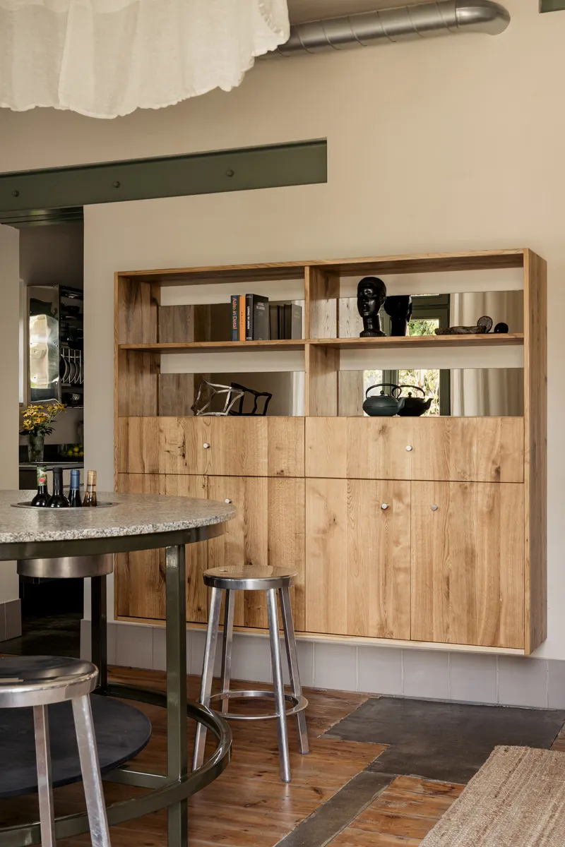 Built-in timber shelving unit with open upper shelves and closed lower cabinets beside a terrazzo island