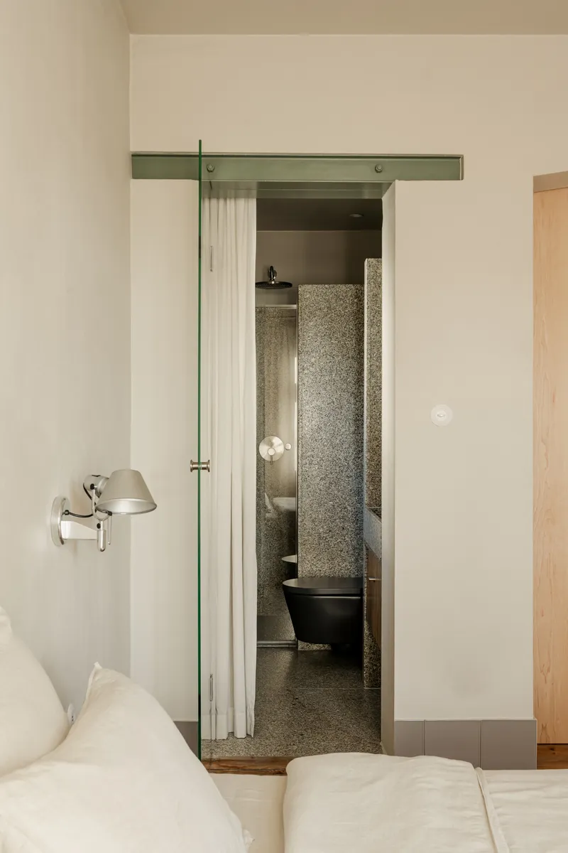 Bedroom view through doorway into bathroom with terrazzo flooring and freestanding black tub