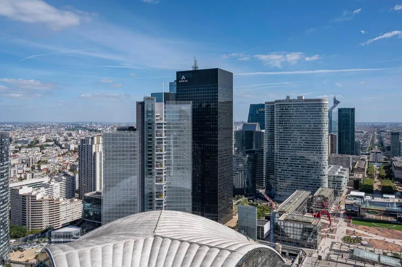 Aerial view of the ribbed shell roof structure surrounded by highrise towers in the urban district