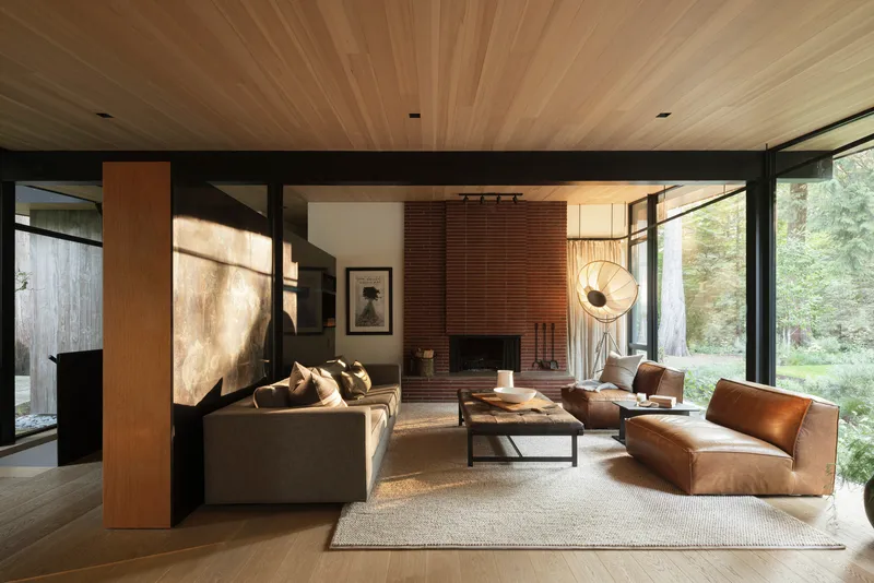 Living room with ribbed wood ceiling, red brick fireplace, and full-height glazing to garden