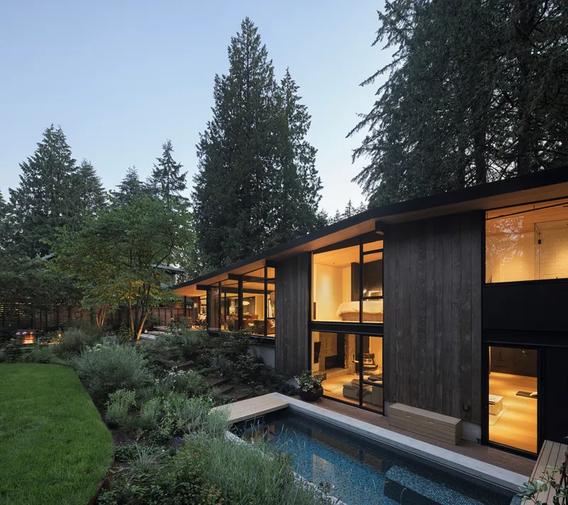 Rear facade with lap pool and planted terraces beneath a darkening sky