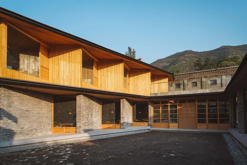 Courtyard elevation with timber screens and exposed roof structure rising above the brick colonnade