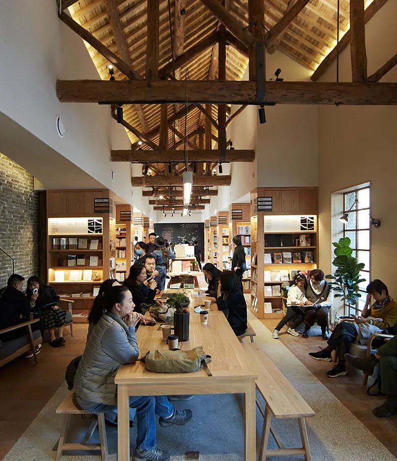 Central seating area with timber benches beneath vaulted ceiling with heavy timber beams and track lighting