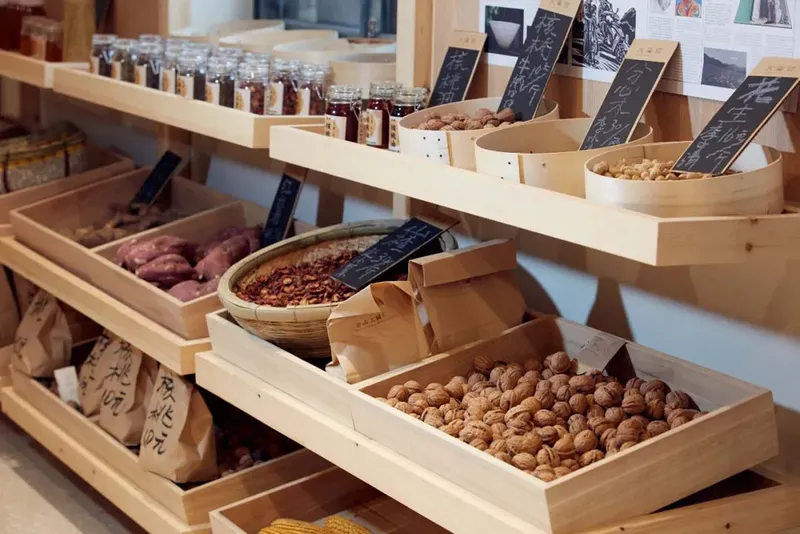 Close-up of angled timber display shelves holding bulk goods in wooden bins with chalkboard labels