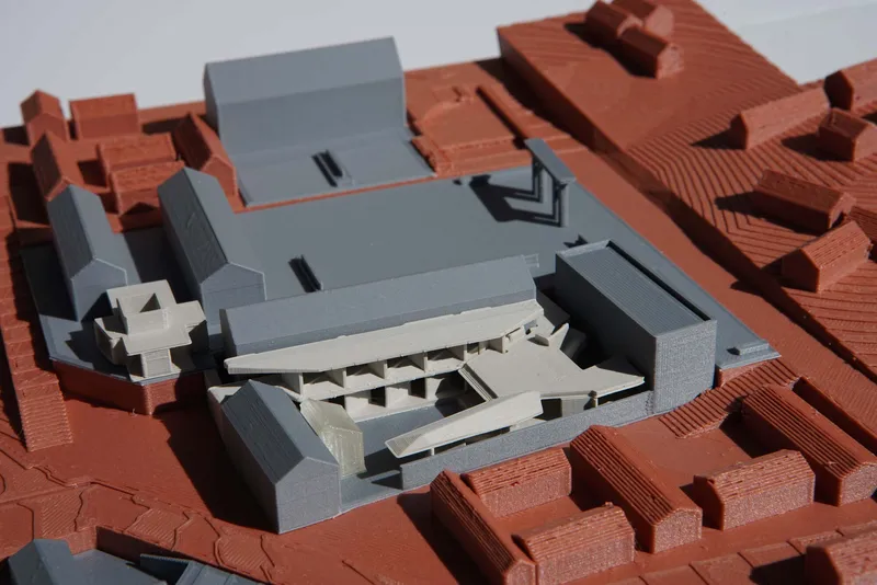 Physical model showing white and grey volumes set within a red tiled roof context
