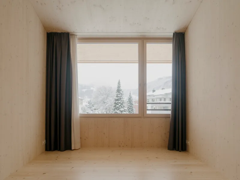 Window alcove framed in timber with view to snow-covered conifers and alpine landscape beyond