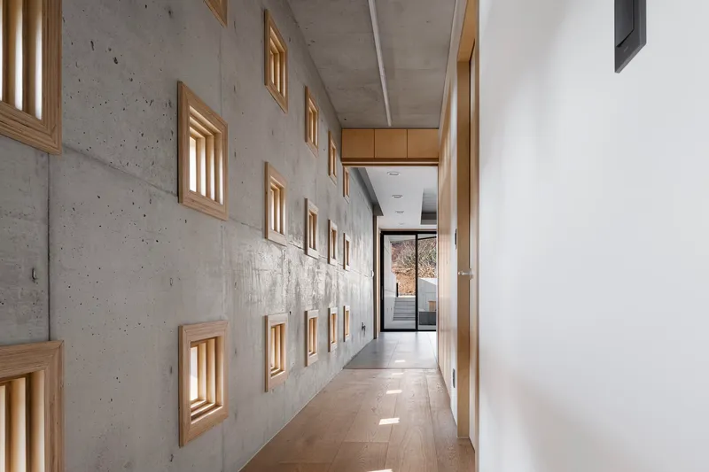 Corridor with timber-framed niches in board-formed concrete wall under exposed ceiling soffit
