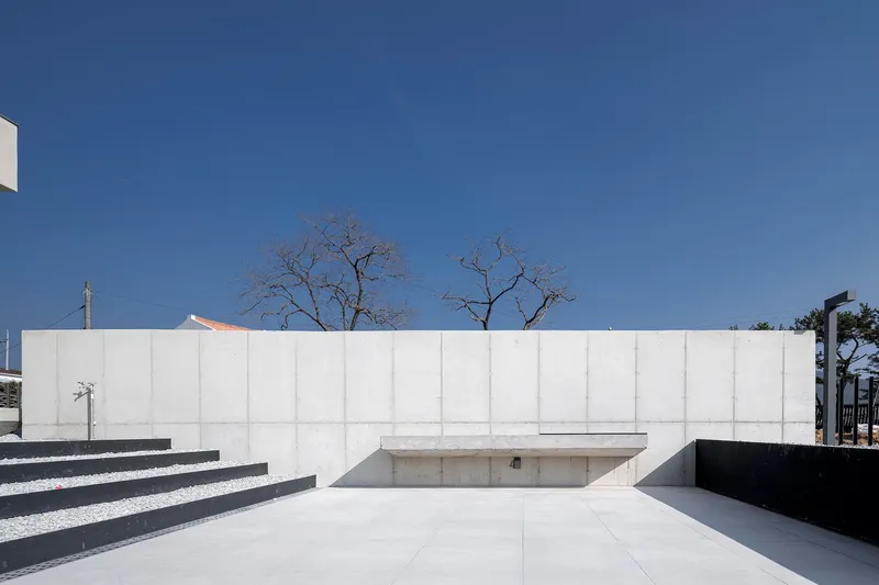 Concrete courtyard wall with recessed steps and sunken pool area beneath bare winter trees