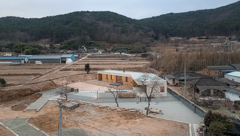 Aerial view of the curved roof volume surrounded by vertical slat fencing in a winter landscape