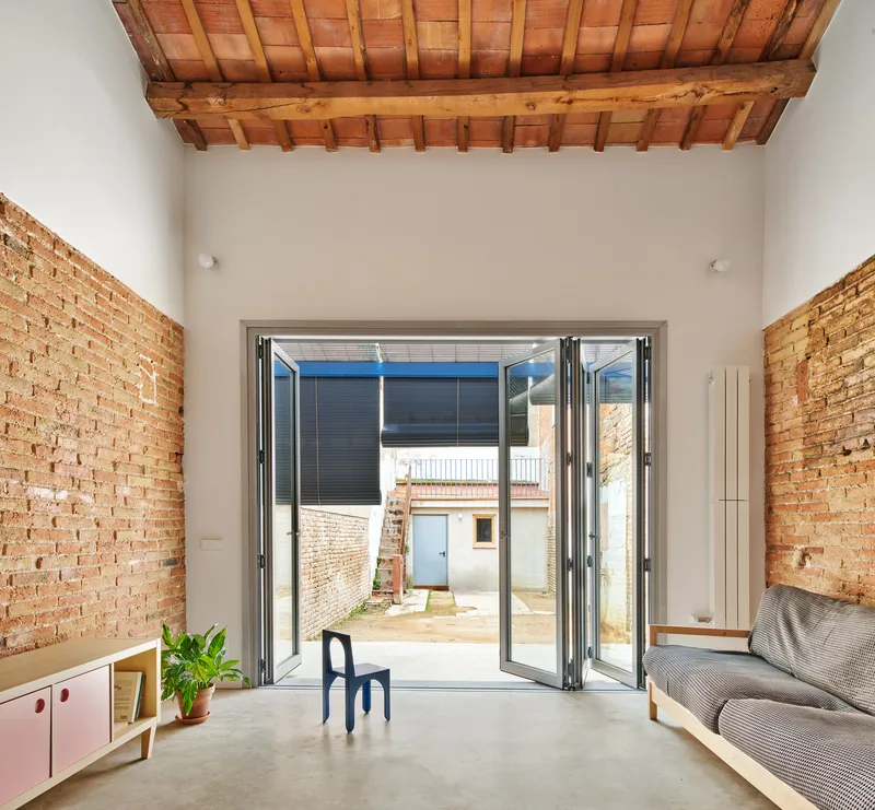 Folding glass doors opening to courtyard flanked by exposed brick walls under timber and tile roof