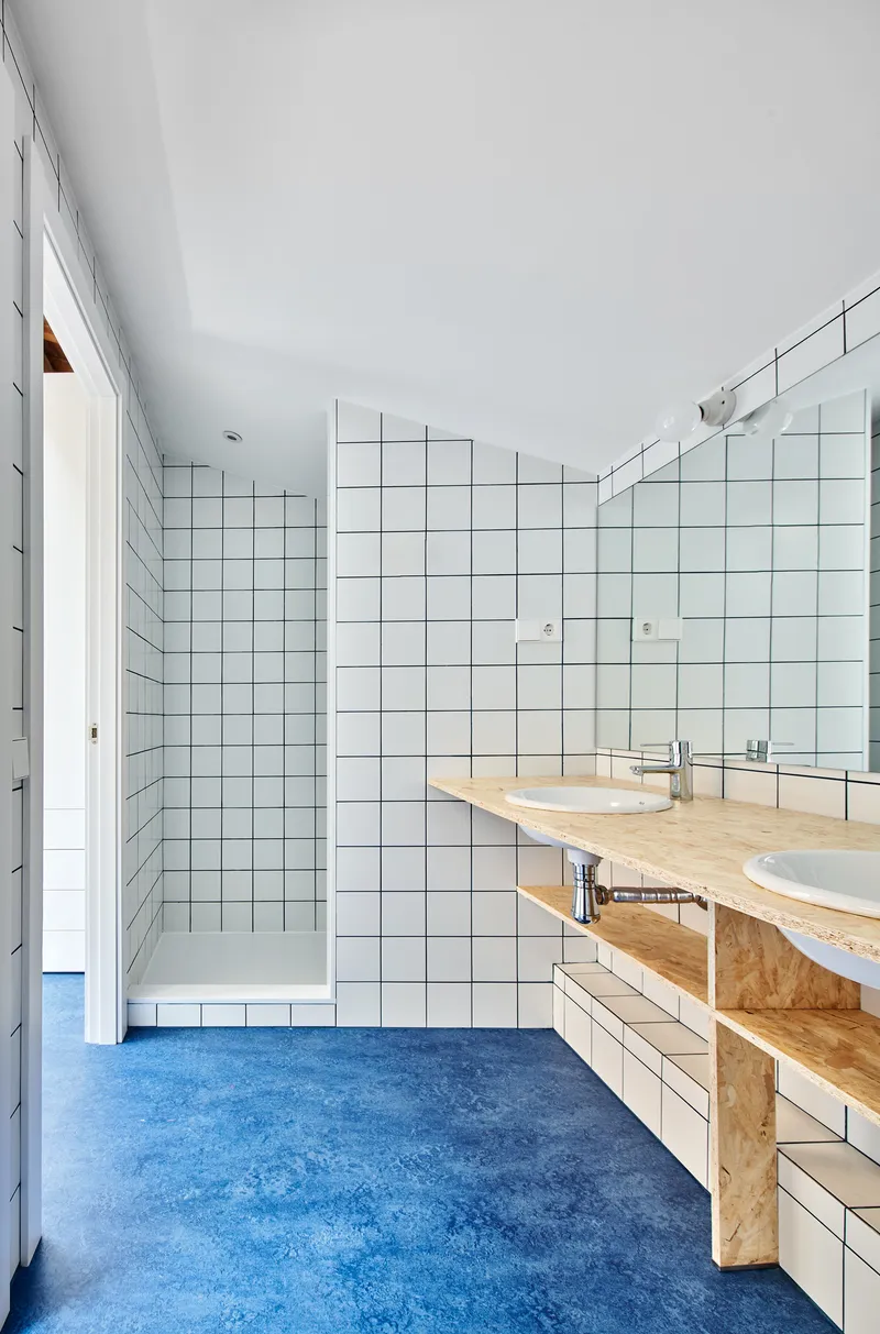 Bathroom with white square tile walls, oriented strand board vanity and blue rubber floor