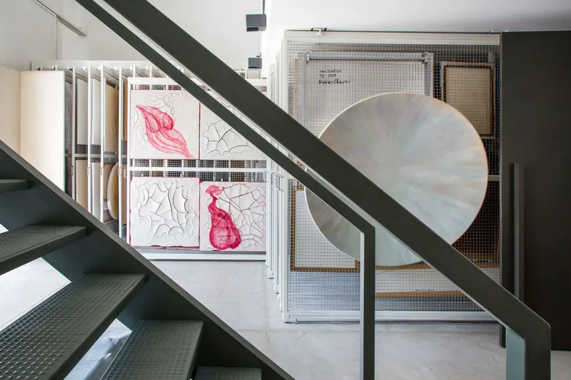 Steel staircase framing a view through wire mesh screens to a balcony with pink fabric artwork
