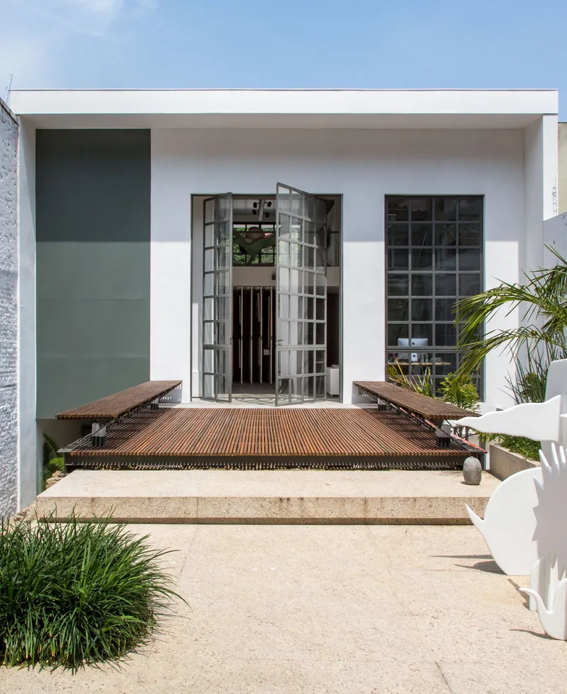 Timber deck bridge connecting to glass block facade openings under a deep cantilevered roof overhang