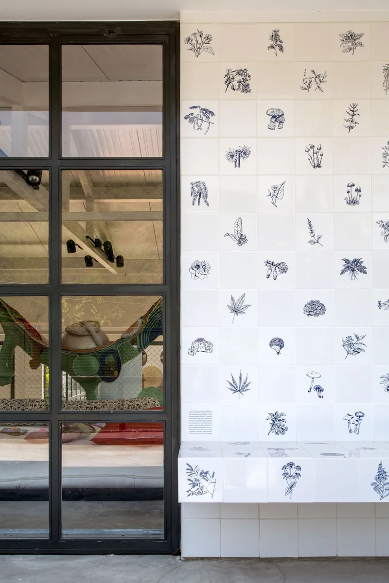Steel-framed glass door opening to an interior staircase beside a white wall with scattered botanical illustrations