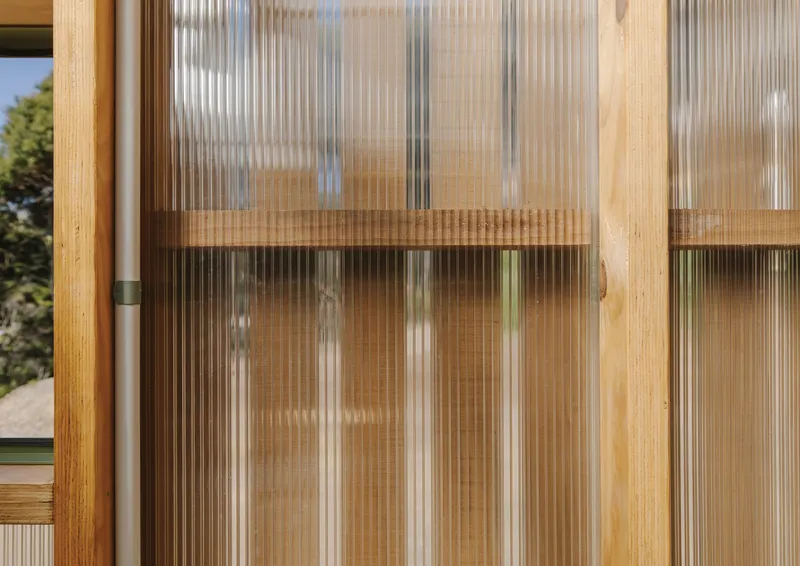 Close-up of fluted polycarbonate sliding door panel with timber frame and horizontal rail detail