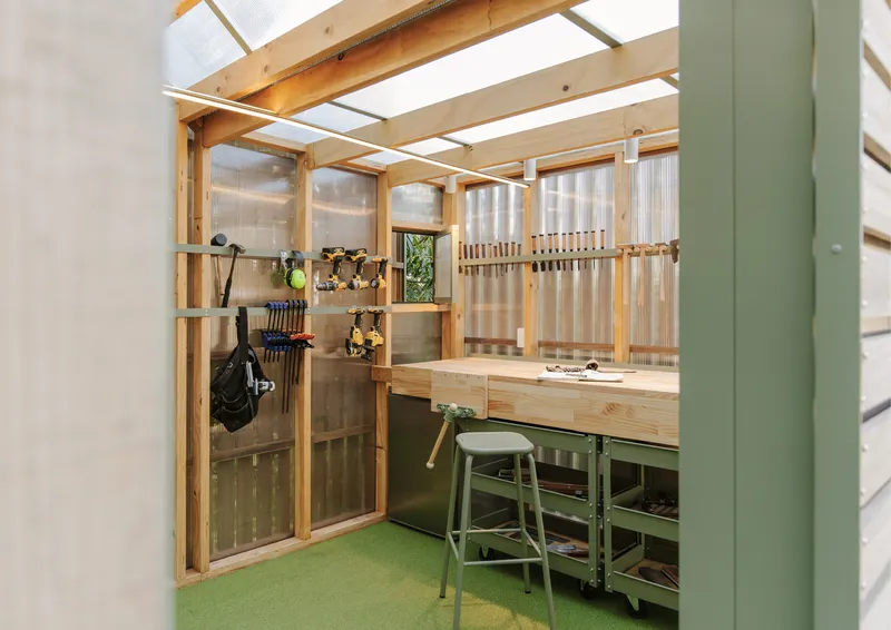 Interior workspace with exposed timber framing, polycarbonate walls, bench and green linoleum floor