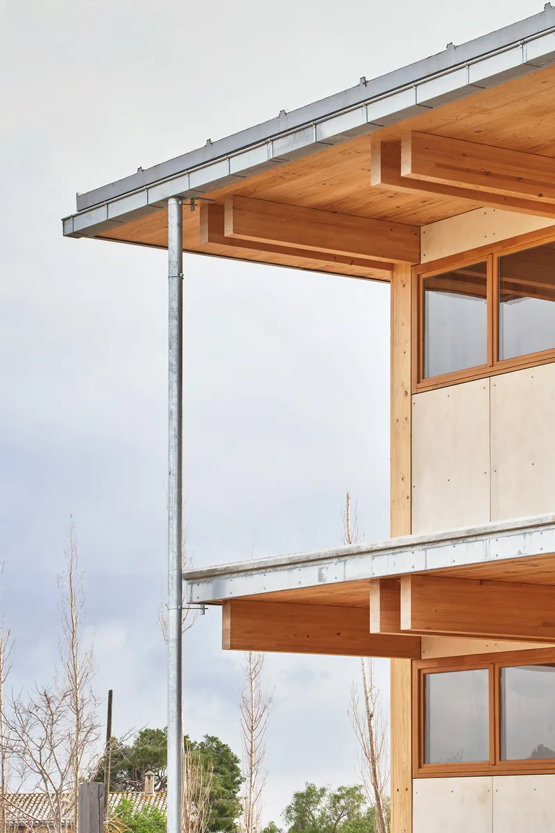 Detail of the stacked timber floors with projecting beams and steel column under cloudy sky