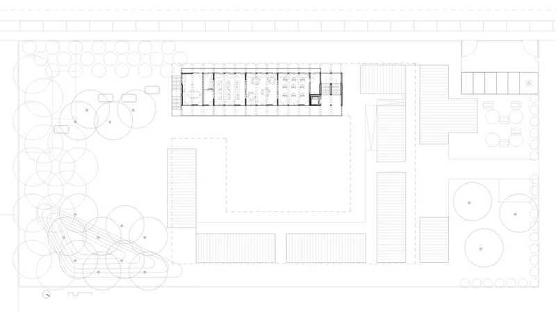 Site plan drawing showing a linear building with courtyard surrounded by landscaped areas and trees