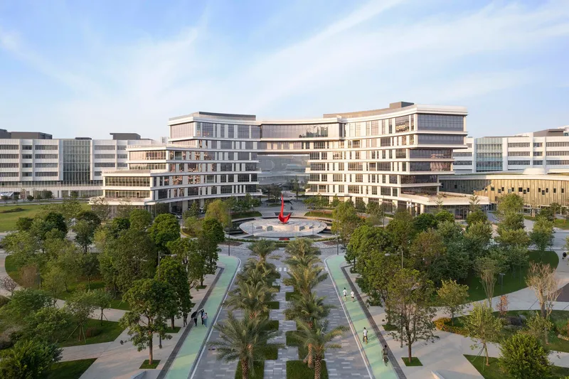 Symmetrical campus buildings flanking a central plaza with fountain and palm-lined pedestrian paths