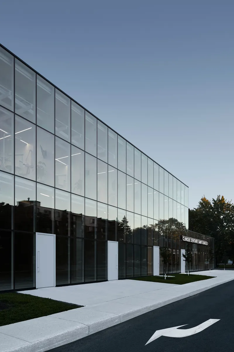 Angled view of the glazed curtain wall with white base panels and lawn edge