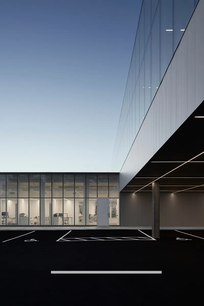 Detail of the corrugated metal soffit meeting the transparent glass wall beside the parking lot