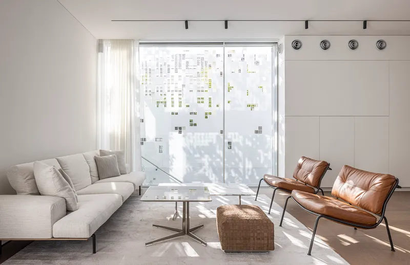 Living area with patterned perforated facade casting filtered shadows across seating and polished concrete floor