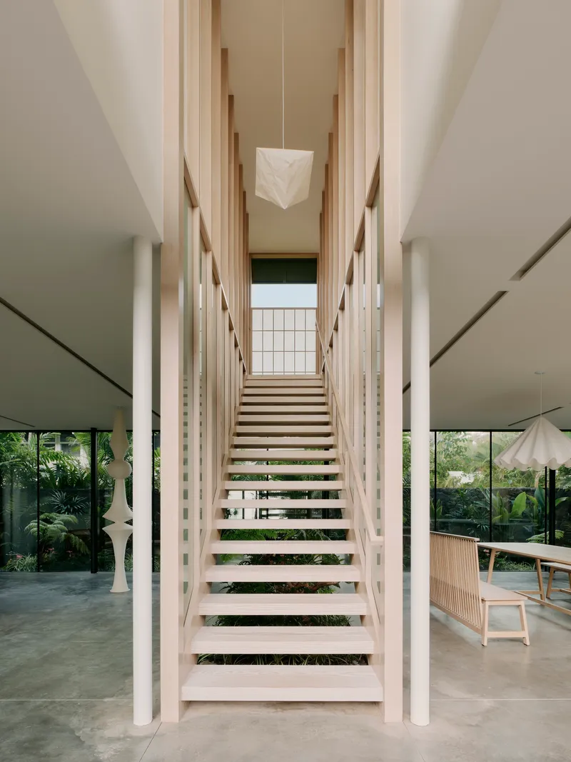 Timber staircase with open treads flanked by white columns and vertical timber slats