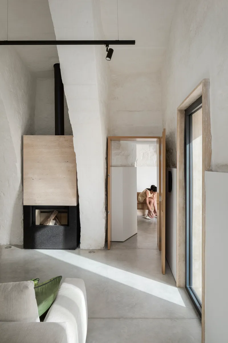 Corner fireplace with black metal hood and timber surround framing a view through an open doorway