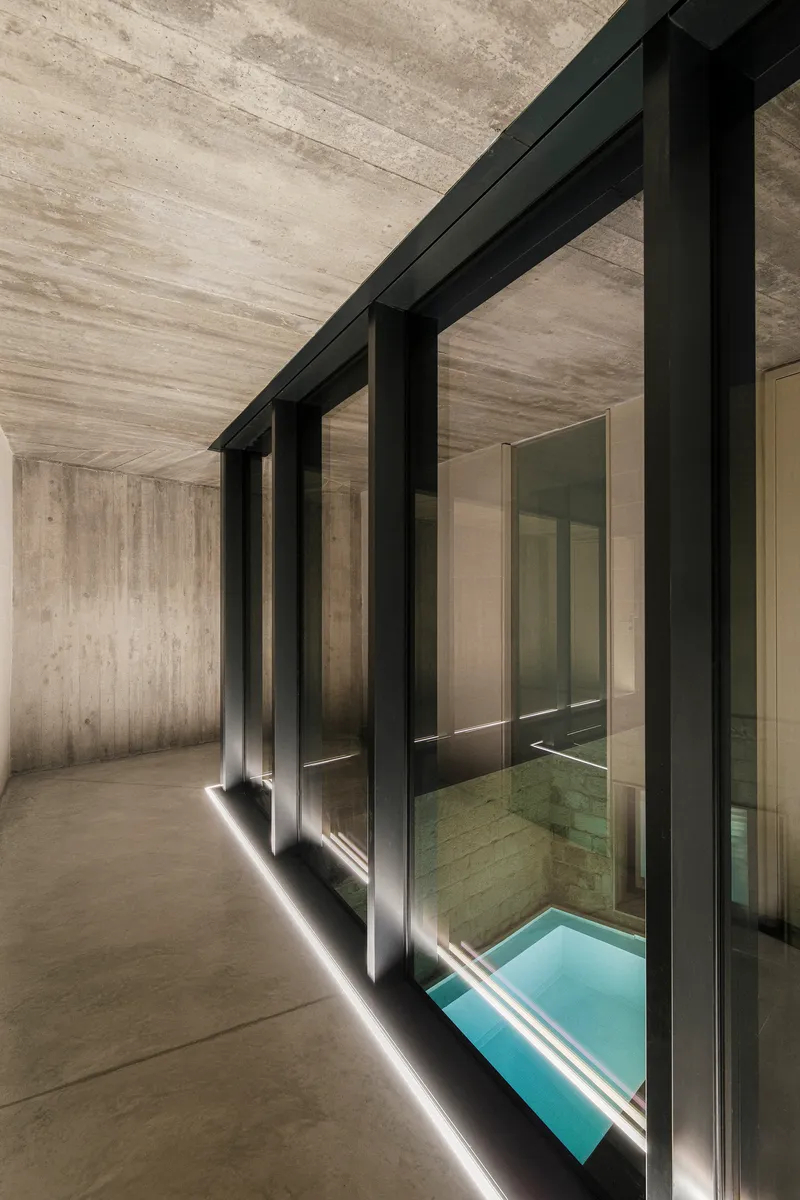 Black steel frame glazing overlooking interior pool with strip lighting along the floor