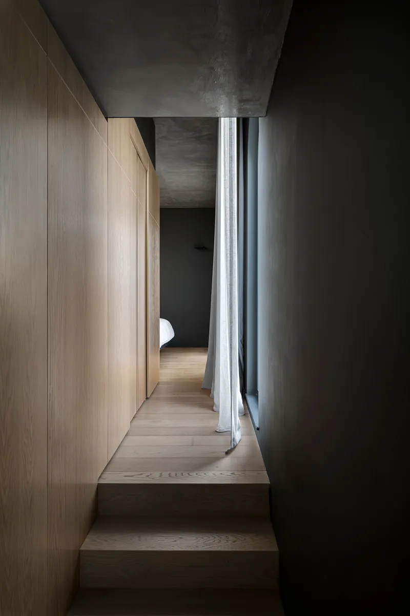 Narrow hallway with timber steps, oak paneling and grey curtains filtering daylight