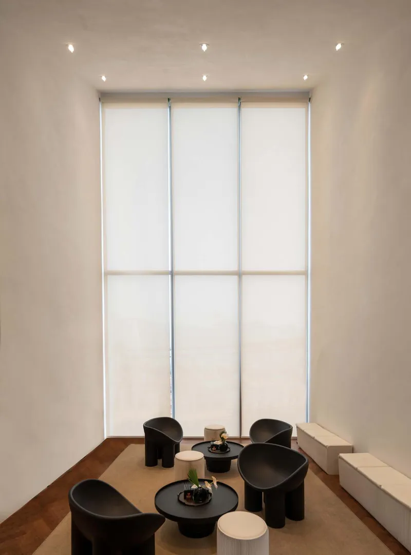 Interior seating area with translucent backlit wall panels and dark circular furniture on timber flooring