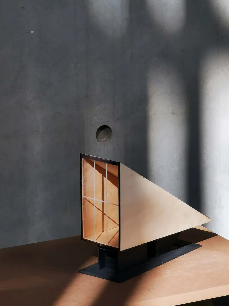 Polished concrete wall with angled daylight falling across a geometric glass door and steps