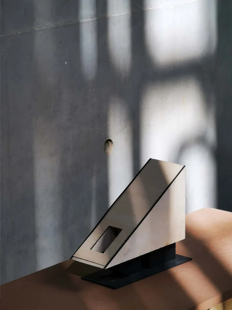 Angular white stair section beside a polished grey concrete wall with soft window shadows