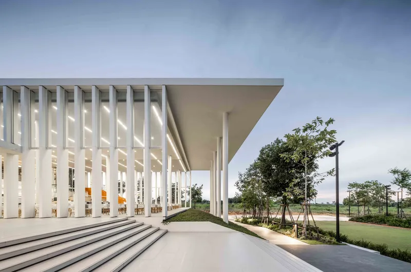 Covered entry plaza with white vertical louvers and deep overhang supported by slender columns