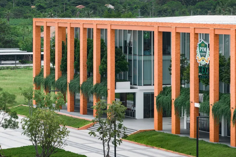 Facade detail with vertical timber fins wrapping glass curtain wall and trailing vines at ground level